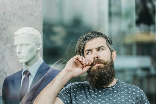 Homme barbu près de vitrine avec mannequin