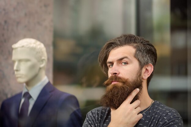 Homme barbu près de vitrine avec mannequin