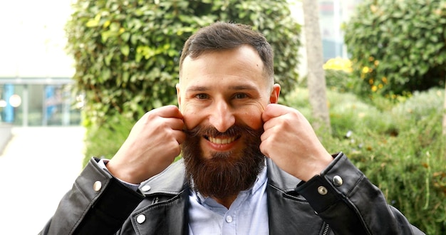 Homme barbu qui boucle sa moustache à l'extérieur et la bouge drôle.