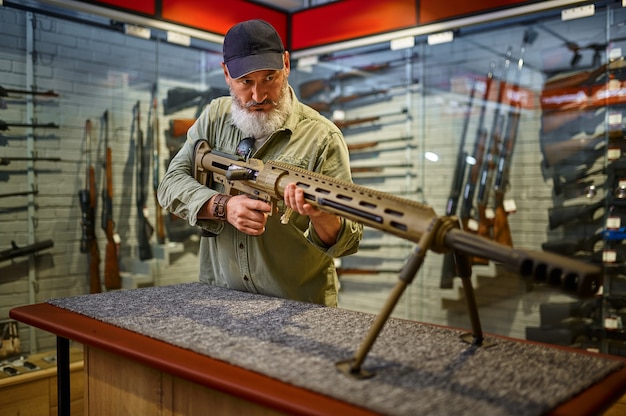 Homme barbu recharger un fusil puissant dans un magasin d'armes à feu