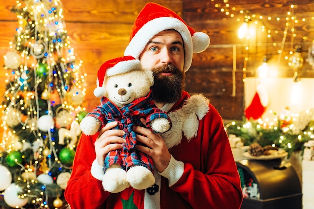 Homme barbu s'amusant près de l'arbre de Noël à l'intérieur