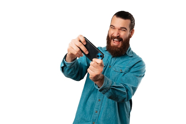 L'homme barbu s'amuse et passe un bon moment en jouant avec son téléphone