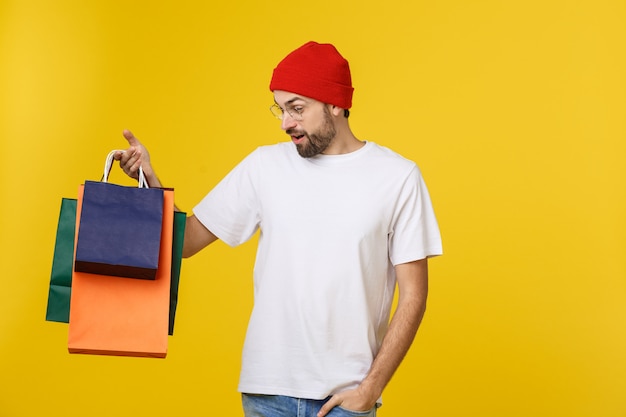 Homme barbu avec des sacs à provisions avec sentiment heureux isolé sur bacground jaune