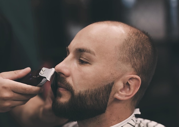 Un homme barbu se coupe la barbe.