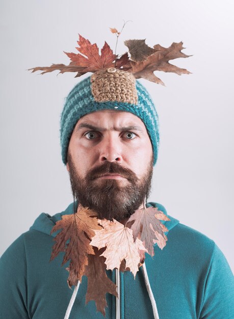 Homme barbu se prépare pour la journée de remise d'automne Homme de mode Surprise homme hipster jouant avec des feuilles et regardant la caméra
