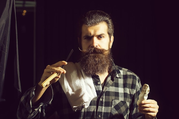 L'homme barbu se rase avec un rasoir