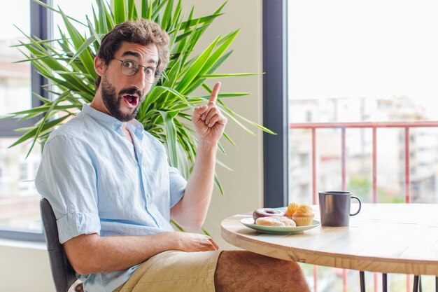 Homme barbu se sentant comme un génie heureux et excité après avoir réalisé une idée, levant joyeusement le doigt, eureka!