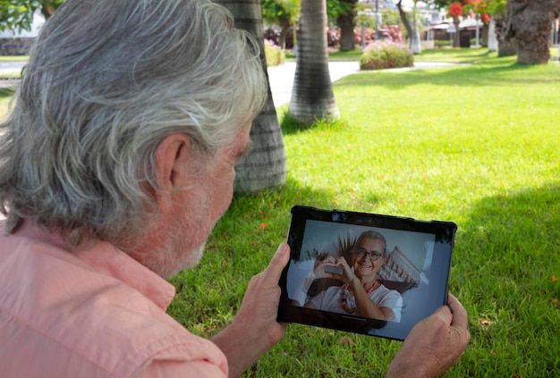 Homme barbu senior parlant avec sa femme lors d'un appel vidéo depuis le jardin à l'aide d'un ordinateur portable conversation numérique personnes âgées technologie et concept de rencontre à distance sociale