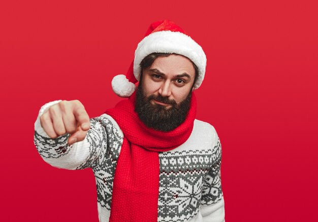 Homme barbu sérieux en bonnet de Noel pointant