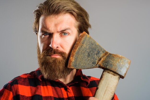 Photo homme barbu sérieux avec vieille hache bûcheron canadien avec hache près du visage closeup portrait