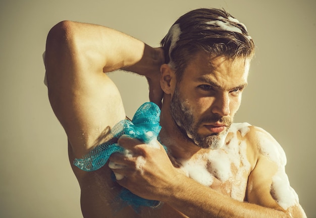Homme barbu sexy lavant le corps musclé bel homme musclé se lavant avec une éponge