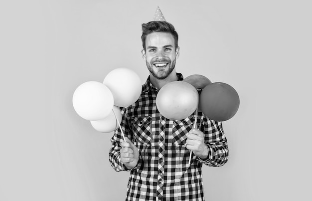 Homme barbu avec des soies tenir des ballons préparation et célébration fête fun shopping vente joyeux anniversaire mec en chemise à carreaux homme élégant avec accessoire de vacances