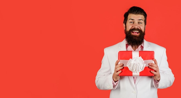 Homme barbu souriant avec boîte-cadeau homme d'affaires en costume avec boîte-cadeau cadeau mec attrayant avec