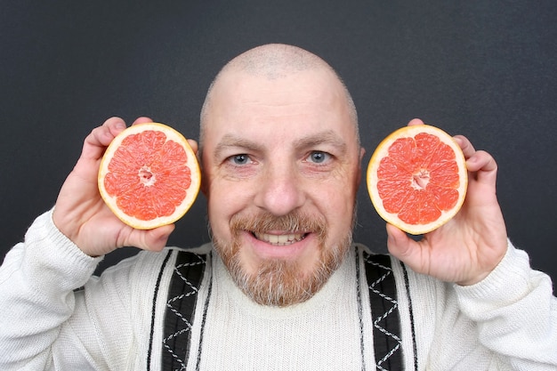 Homme barbu souriant avec un pamplemousse coupé dans ses mains