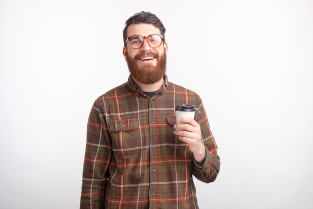 Homme barbu souriant profite de son café du matin pour aller sur fond blanc.