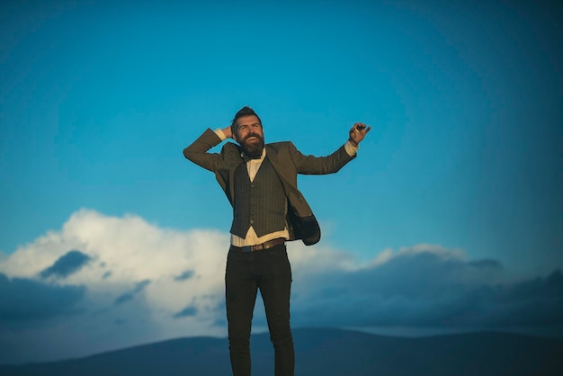 Homme barbu sourire avec cigarette sur paysage naturel homme barbu fumeur à l'air frais