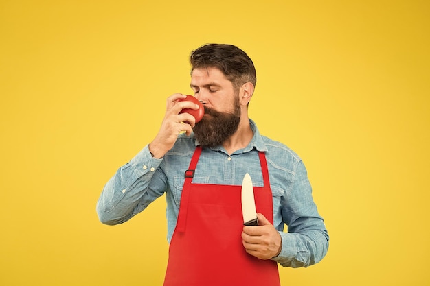 Homme barbu en tablier avec couteau à trancher renifler une plante de tomate rouge mûre fraîche odeur délicieuse