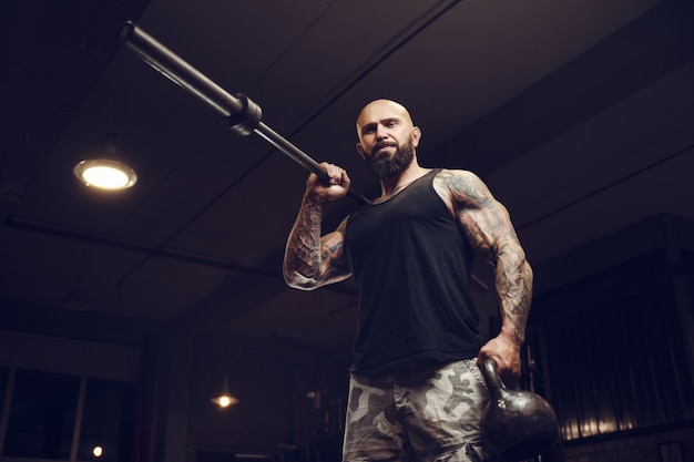 Homme barbu tatoué brutal dans la salle de gym