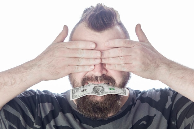 Homme barbu tenant un dollar dans sa bouche et ferme les yeux avec ses mains