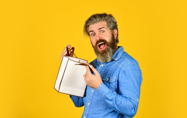 Homme barbu tenant des sacs à provisions Concept de vente au détail Joyeuses fêtes Bel acheteur Vente saisonnière Augmenter les ventes Hipster achetant le prix de vente Black Friday Cyber lundi vente Bel achat Acheter un cadeau