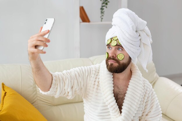 Homme barbu tenant des tranches de concombre sur le visage spa à la maison corps et soins de la peau pour le concept masculin