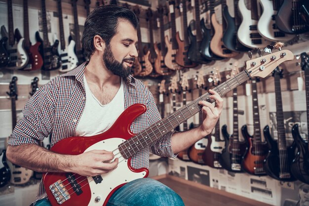 Homme barbu vérifiant nouvelle guitare dans le magasin de musique