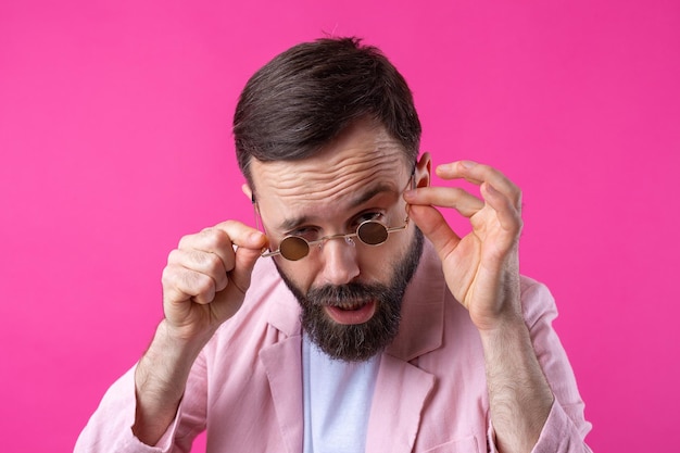 Homme barbu vêtu d'une veste rose avec des lunettes Portrait en studio émotionnel