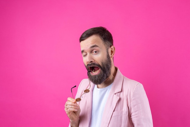 Homme barbu vêtu d'une veste rose avec des lunettes Portrait en studio émotionnel