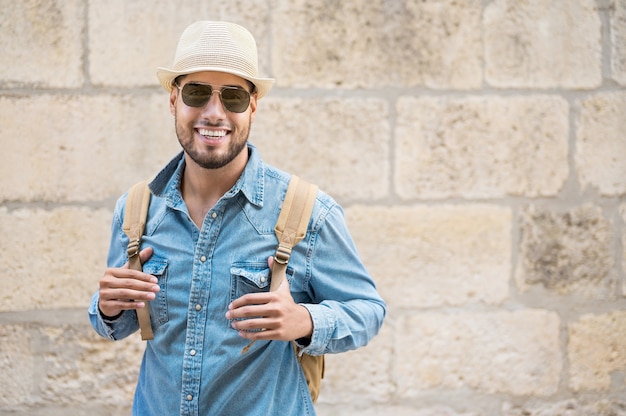 Photo homme barbu de voyageur élégant au chapeau posant en regardant le concept de voyage et d'envie de voyager de la caméra