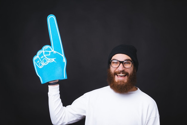 Un homme bardé souriant pointe avec un grand gant d'éventail pour copier l'espace.