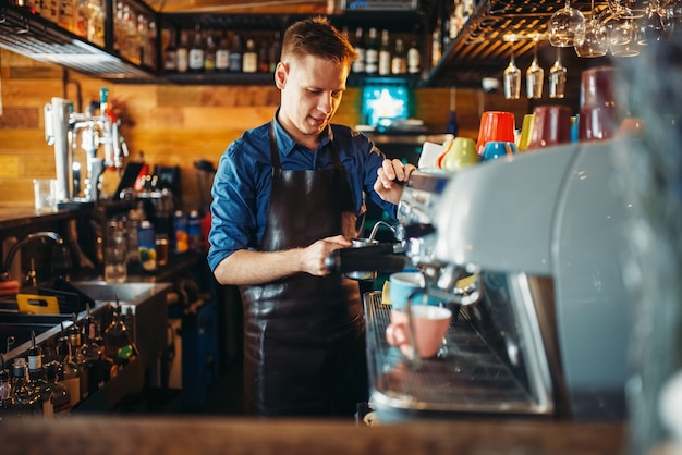 Homme barman prépare un verre au comptoir du bar