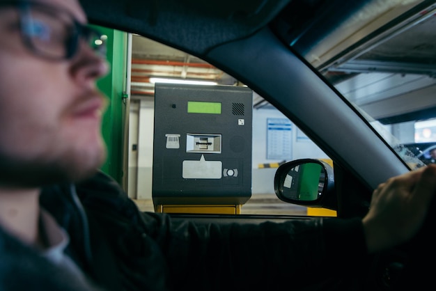 Homme de barrière de stationnement prenant un ticket pour passer le contrôle sur l'aire de stationnement