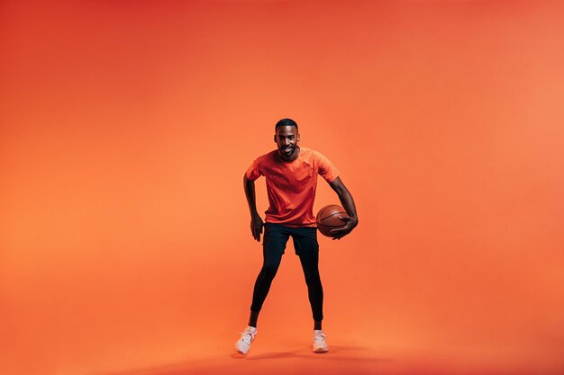 Photo un homme avec un basket-ball sur un fond orange