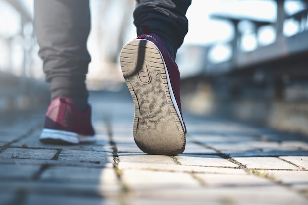 L'homme en baskets marche dans la rue par une journée ensoleillée