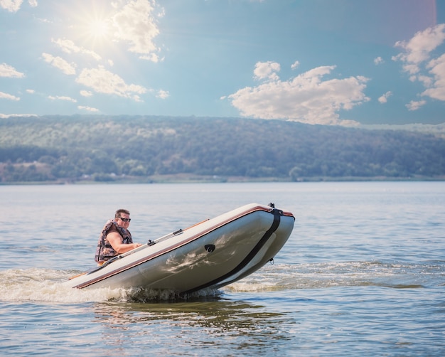 Homme en bateau à moteur en caoutchouc. Concept de liberté et de mouvement