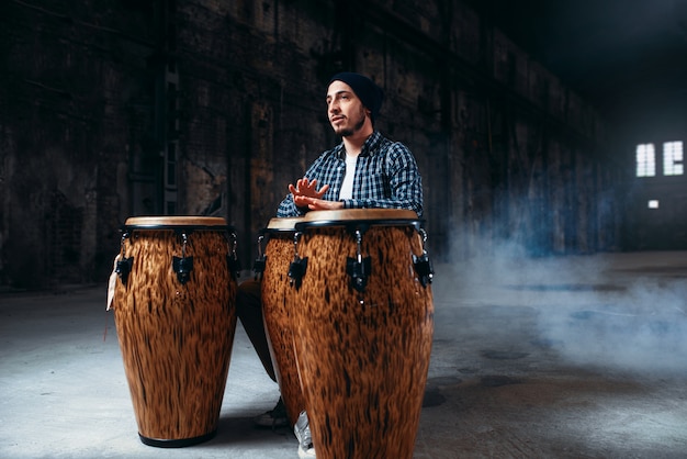 Photo homme batteur joue sur des tambours en bois en magasin d'usine