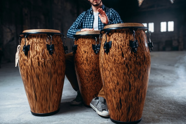 Homme batteur joue sur des tambours en bois en magasin d'usine