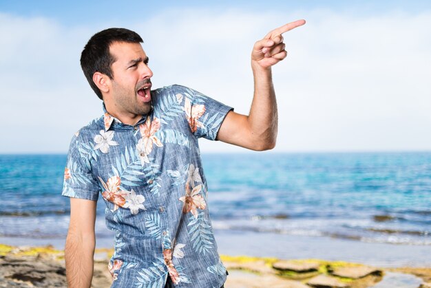 Homme beau avec une chemise à fleurs dansant à la plage