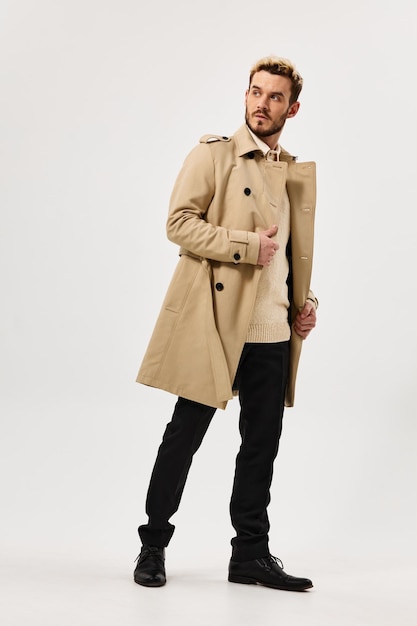 Homme beau en manteau beige style d'automne studio pleine croissance vue latérale photo de haute qualité