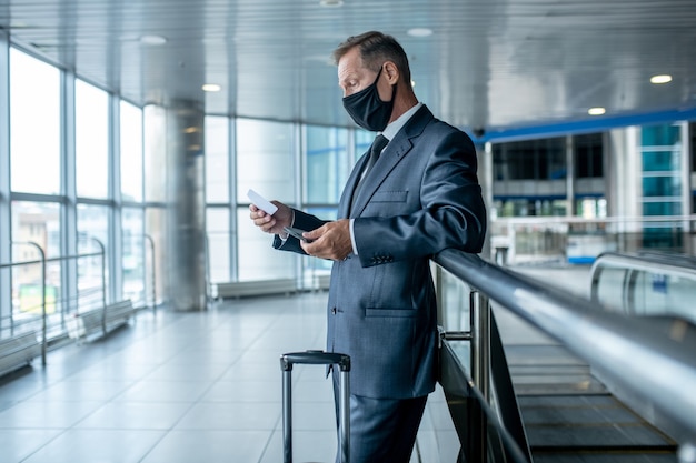 Homme avec billet et valise dans le hall de l'aéroport