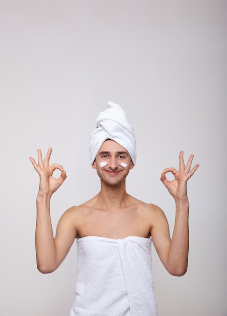 Un homme blanc heureux après le spa montre à ses mains un signe de ok.