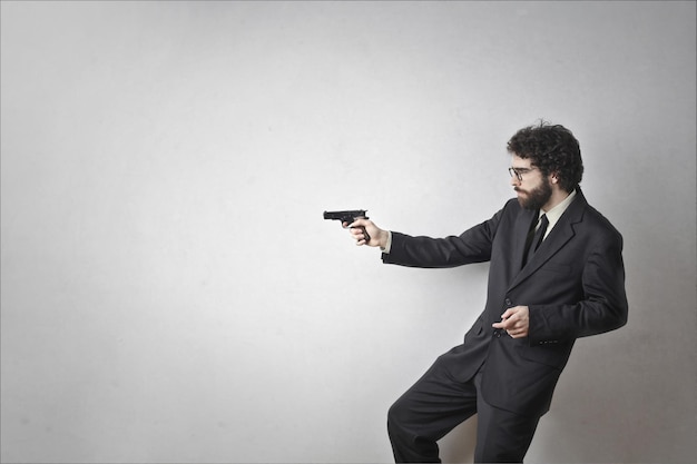 homme blanc tire avec un pistolet sur fond gris