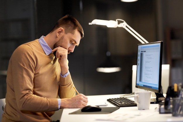 homme avec un bloc-notes travaillant sur le code au bureau de nuit