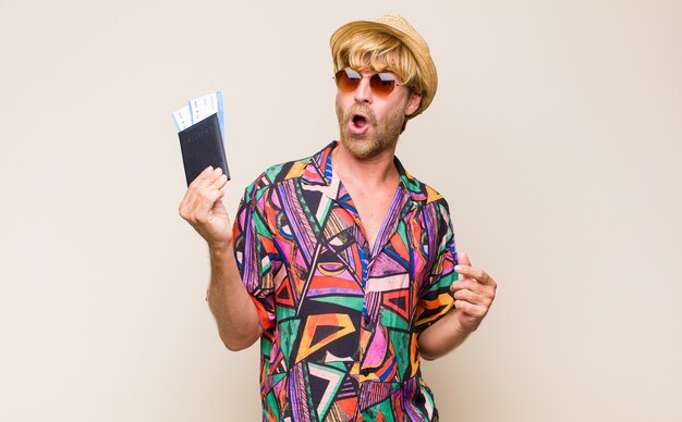 Homme blond adulte avec un passeport et des billets d'avion d'embarquement