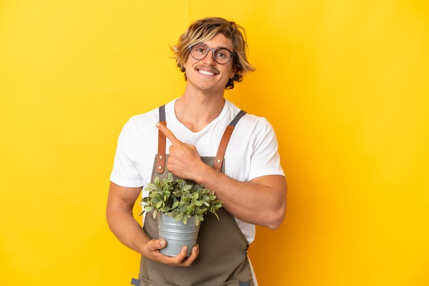 Homme blond jardinier tenant une plante isolée