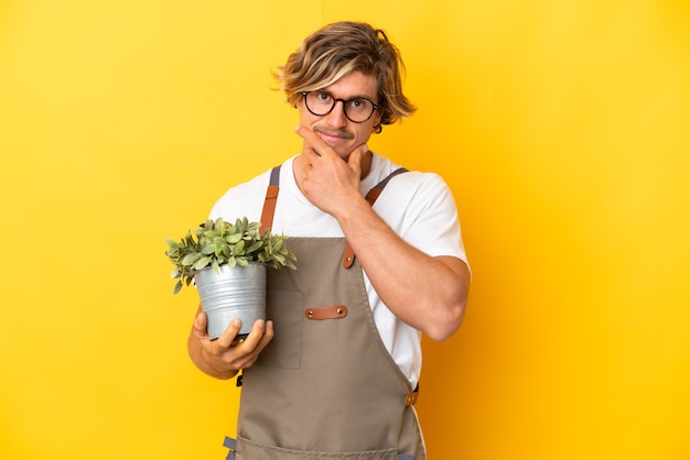 Homme blond jardinier tenant une plante isolée