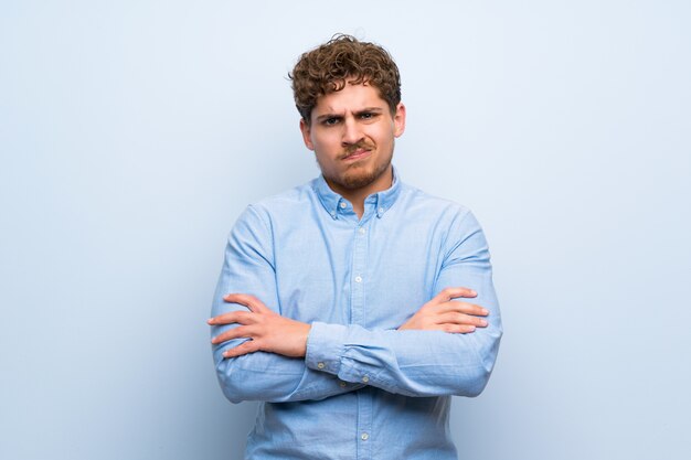 Homme blond sur mur bleu se sentir bouleversé