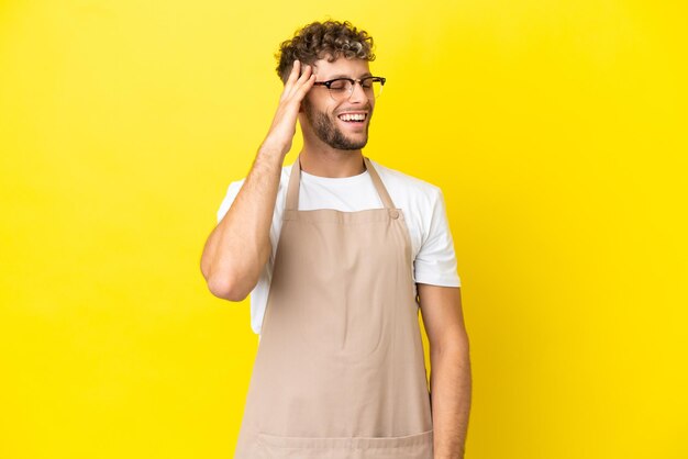 L'homme blond de serveur de restaurant d'isolement sur le fond jaune a réalisé quelque chose et a l'intention de la solution