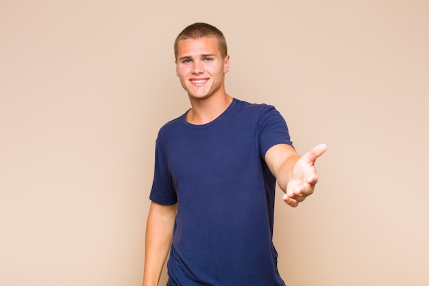 Homme blond souriant, heureux, confiant et sympathique, offrant une poignée de main pour conclure un accord, coopérant