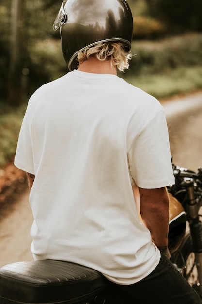 Homme blond en t-shirt blanc assis sur un vélo avec espace design